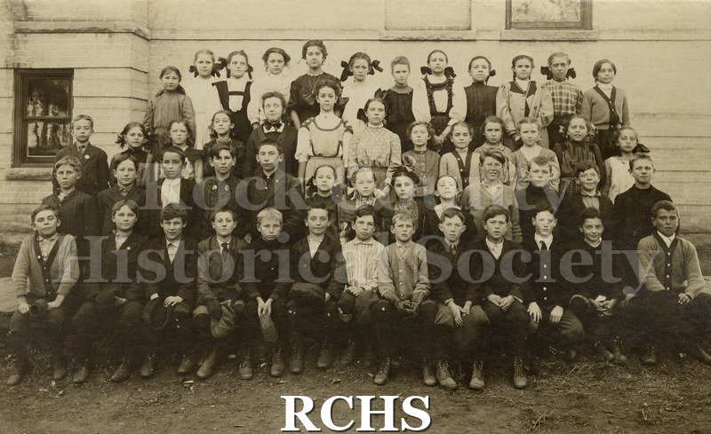 Black and white photograph of Evansville Grade School. Shows a group of school children sitting and standing in front of a school.