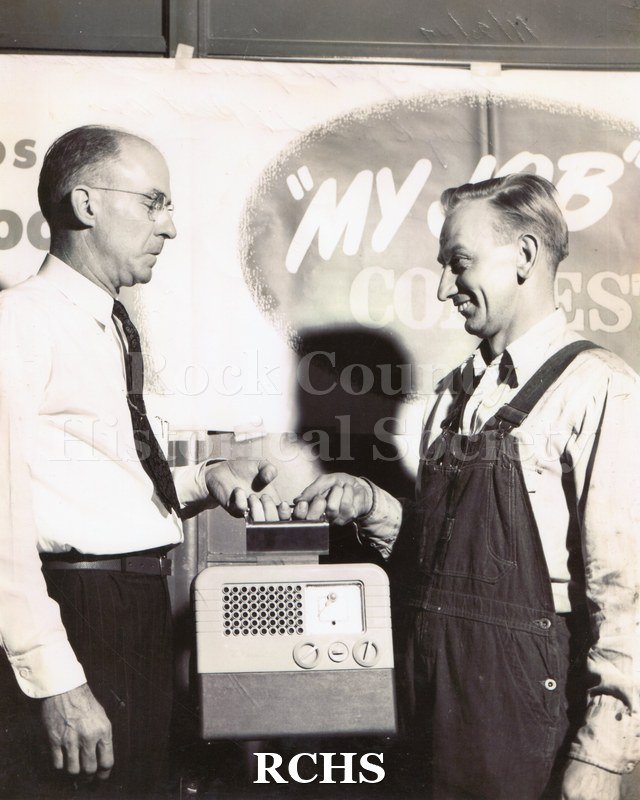 Black and white portrait of Clarence Dittmer receiving a portable radio for his entry into the GM "My Job and Why I Like It" corporate competition in 1947.