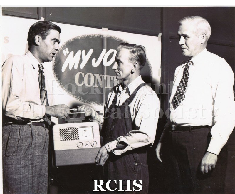 Black and white portrait of Clarence Dittmer receiving a portable radio for his entry into the GM "My Job and Why I Like It" corporate competition in 1947.