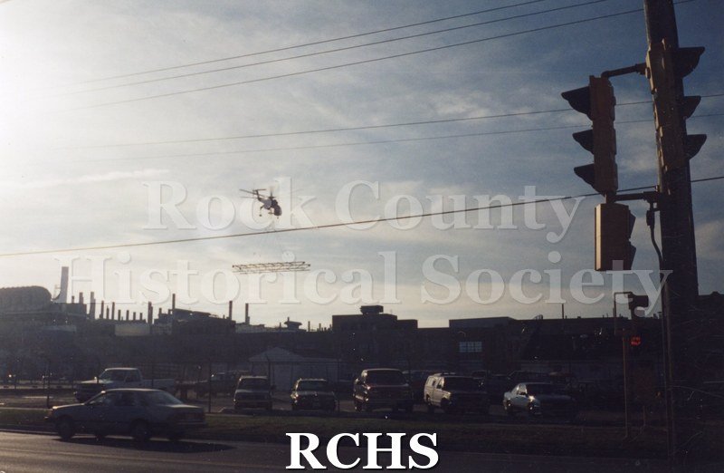 Color photo of a helicopter dropping off building materials to the roof of a building at General Motors. Photo was taken by Ronald Nelson when he was a GM employee.