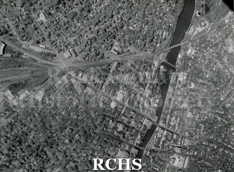 Black and white photograph of an aerial view of downtown Janesville. Five Points to the Court House with the Milwaukee Road Roundhouse on the left hand side of the.