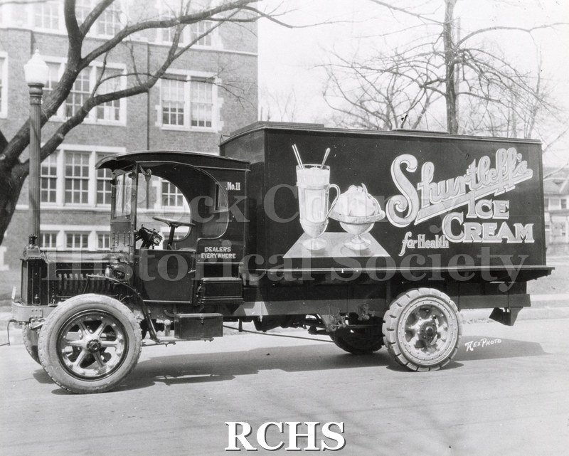 Black and white photograph of a Shurtleff Ice Cream Company delivery truck, which appears to be parked in front of Janesville High School.