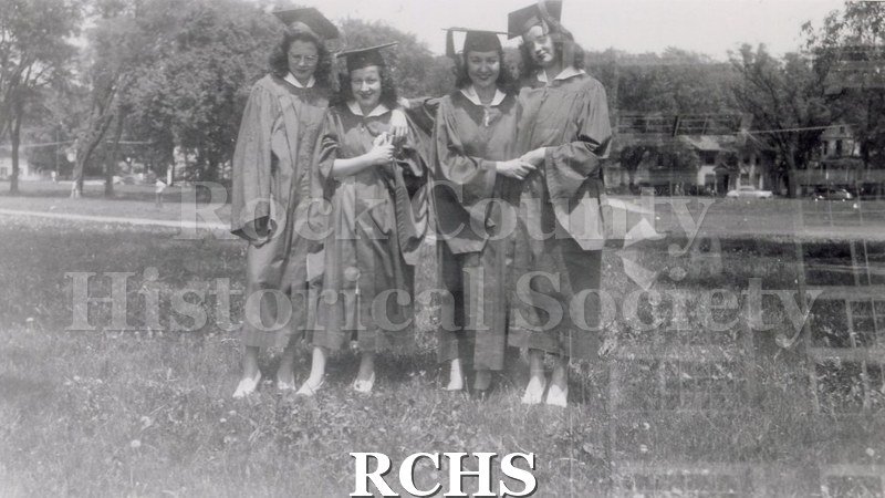 Black and white photograph of Jean McLaughlin and friends in cap and gown as they graduate from Janesville High School.
