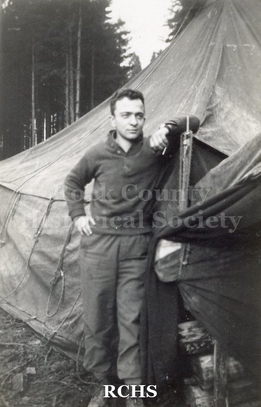 Black and white photograph of an unidentified soldier posed outside a tent. Harvey Thompson (1920 - 1978) lived at 213 Water Street in Janesville.