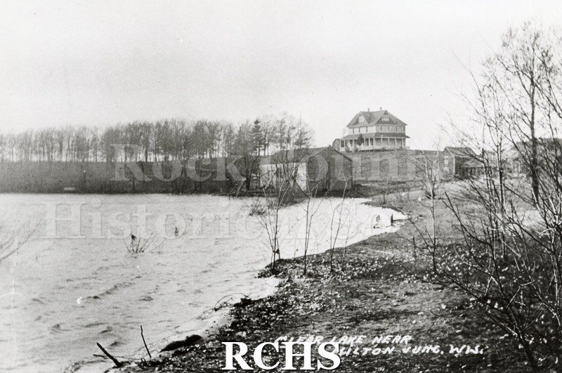 Black and white photograph of a large farm house on a hill overlooking Clear Lake near Milton.