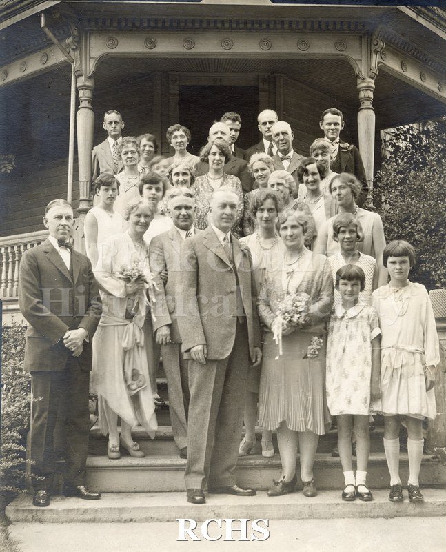 Black and white photograph of Mr. and Mrs. George K. Tallman's wedding party standing on the steps of a house, likely the Academy Street House.