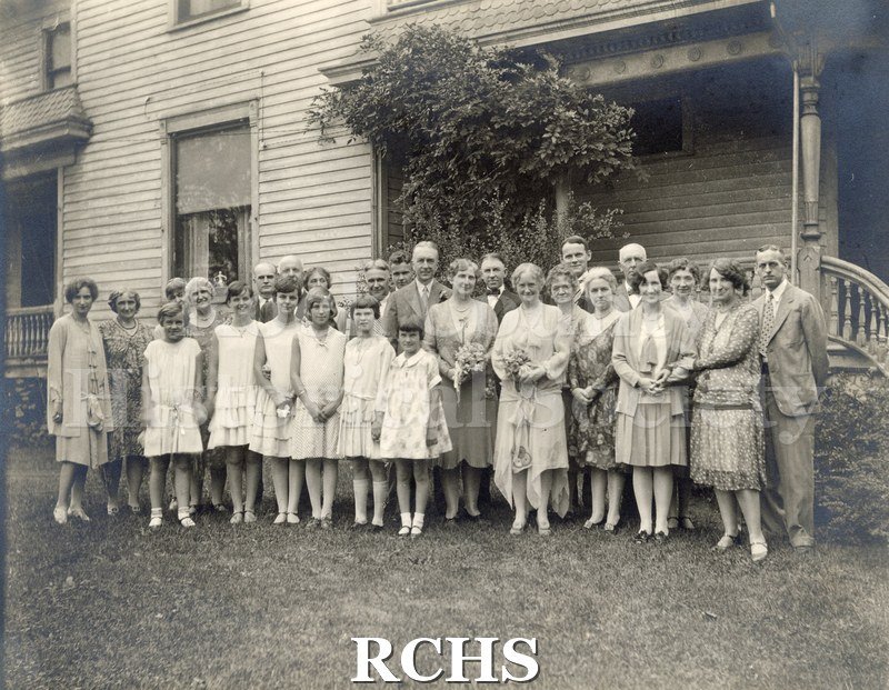 Black and white photograph of Mr. and Mrs. George K. Tallman's wedding party standing on the lawn in front of a house, likely the Academy Street home.