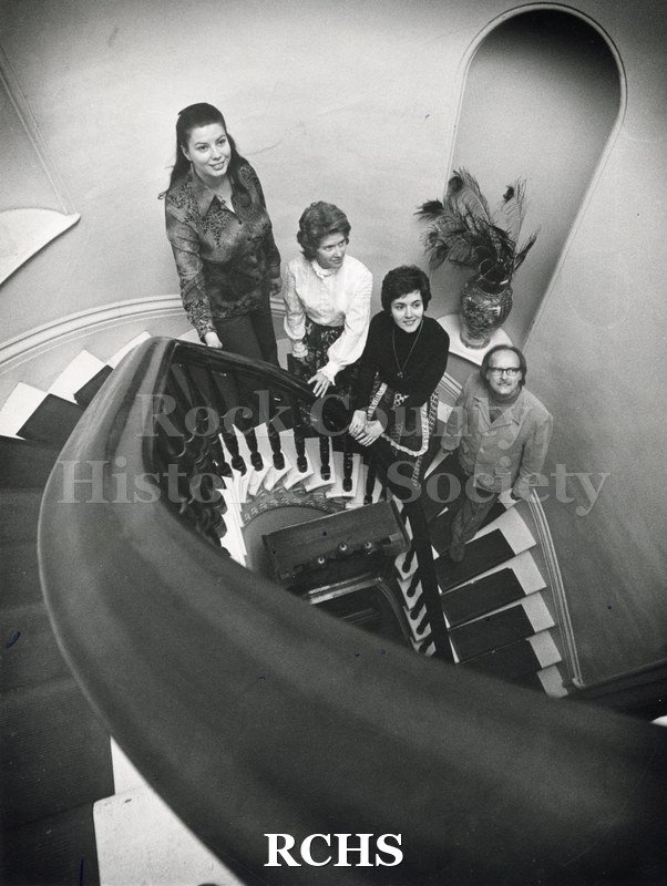 Black and white photograph of the Tallman House stairway. Four people are standing on the staircase in the Tallman House.