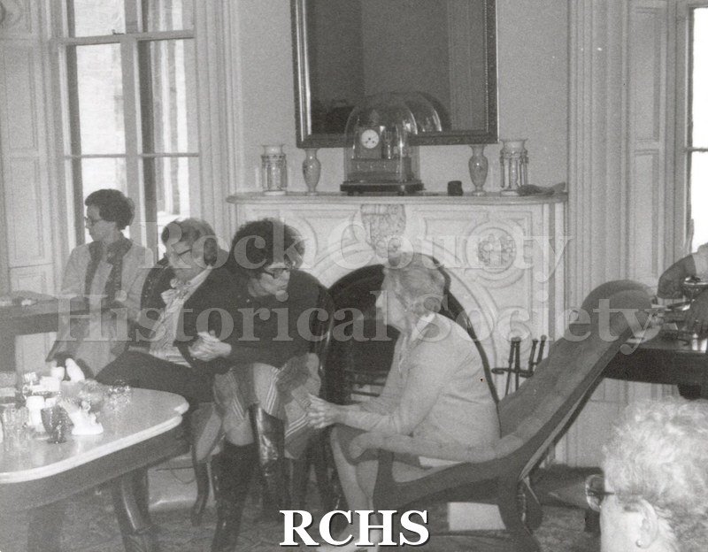 Black and white photograph of four unidentified women sitting in front of the fireplace in the Tallman House.