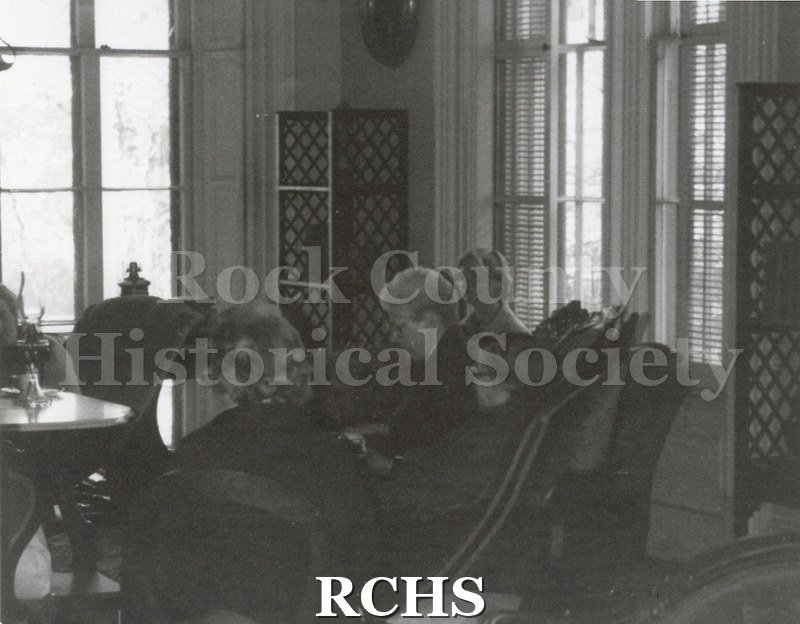 Black and white photograph of three women sitting on a settee in the Tallman House.