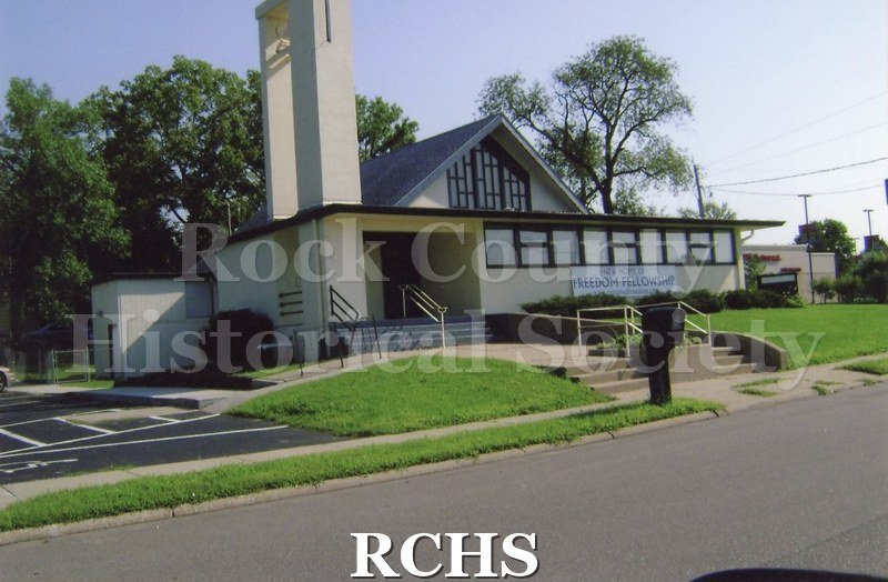 Colored photograph of Freedom Fellowship, 1849 Bayliss Ave., Beloit. Cream color building with dark brown trim.