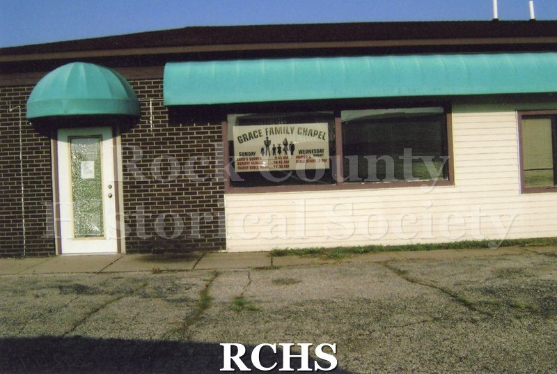 Colored photograph of Grace Family Chapel, non-denominational, 2912 S. Bartells Dr., Beloit. Cream siding with dark brick. Turquoise awning.