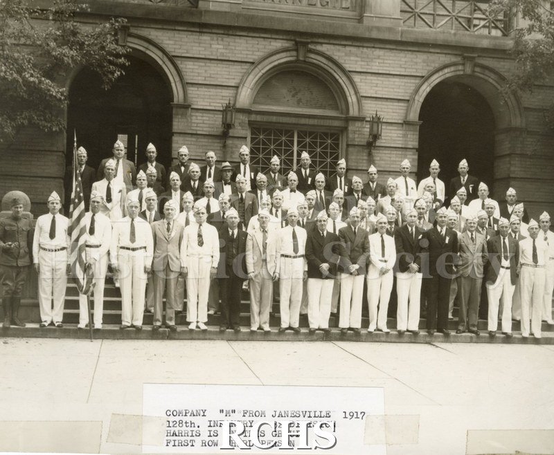 Black and white photograph of 1920 reunion Company "M", 128th Infantry, 32 Division. Shows five rows of men standing in front of Carnegie Library in Janesville.