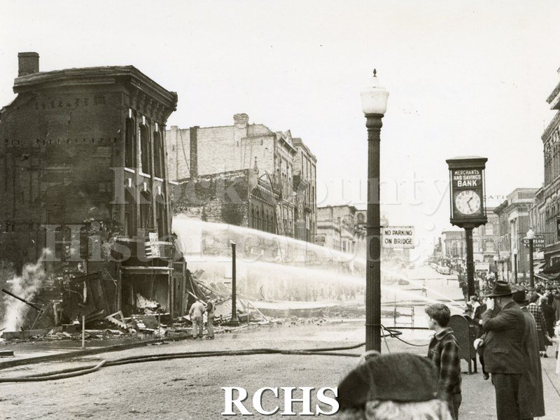 Black and white photograph of Janesville Fire 1942. Buildings on left with streams of water on it.