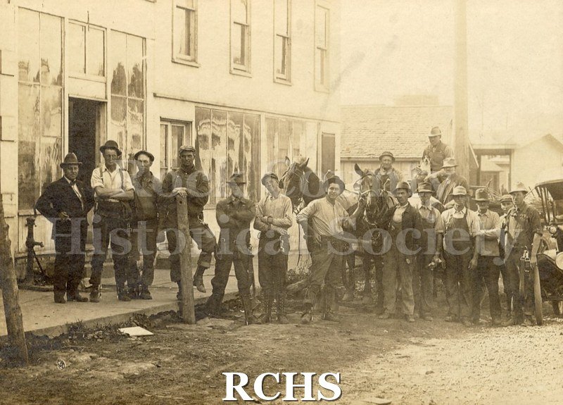 Black and white photograph of men of the Electrical Paver Crew, based in Clinton, with their horses, standing in front of an unknown building.