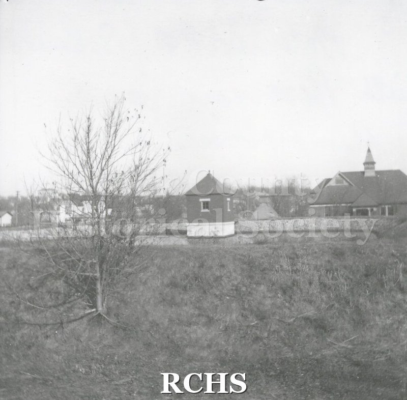 Black and white photograph of the Janesville Water Works on S. River Street with the reservoir and pump house visible at the center.