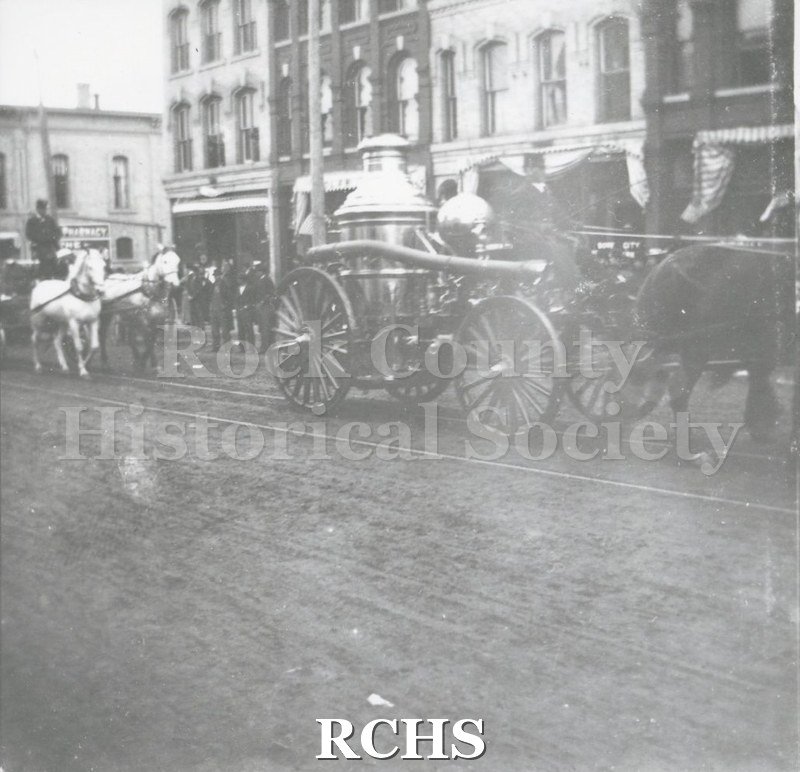 Black and white photograph of the Water Witch pumper in a parade in Janesville.