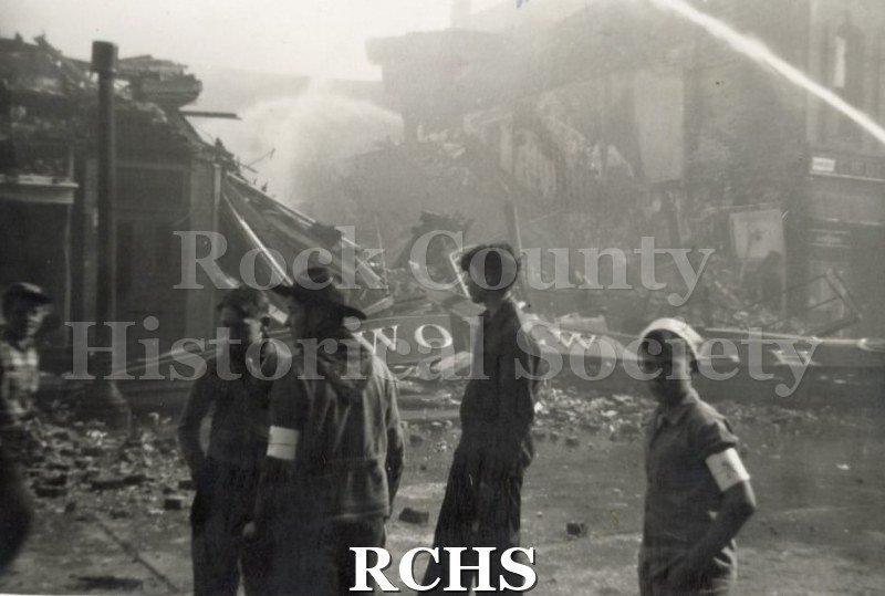 Black and white photograph of the Janesville Fire Milwaukee Street 1942. Shows men standing in front of a fire.
