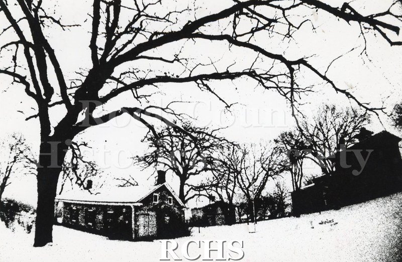 Black and white photograph of the Tallman Restorations. Shows the back of the Stone House and Tallman House with snow on the ground.