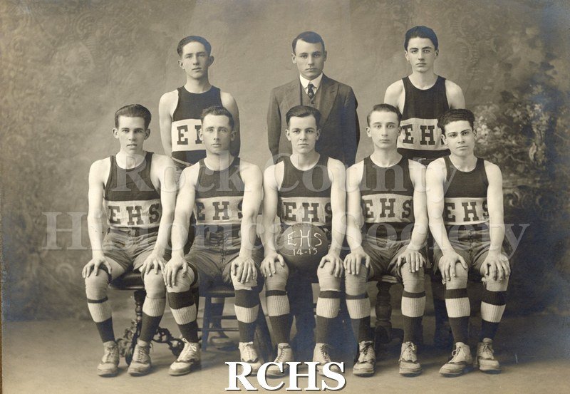 Black and white photograph of Evansville High School Basketball Team 1914-1915. There are seven young men in the uniform of Evansville High School.