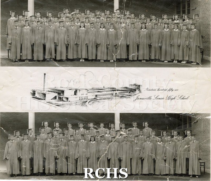 Black and white photograph of Janesville Senior High School 1956. Shows men and women in graduation gowns and caps standing in front of brick building with white.