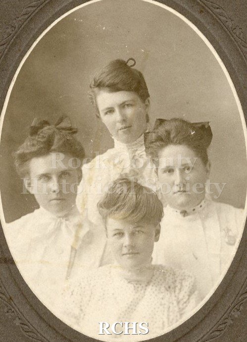 Black and white photograph of Tillie Acheson, Edith Andrews, Grace Clark, and Hally Weaver, the four women shown, each with hair on top of head and wearing white.