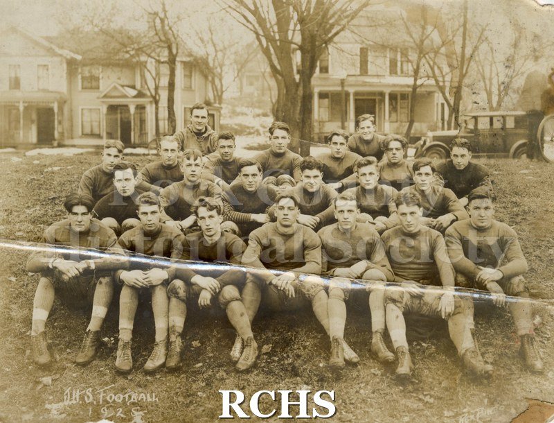 Black and white photograph of Janesville High School football team. Players seated outside in three rows. "J.H.S. Football/1925" printed on bottom.