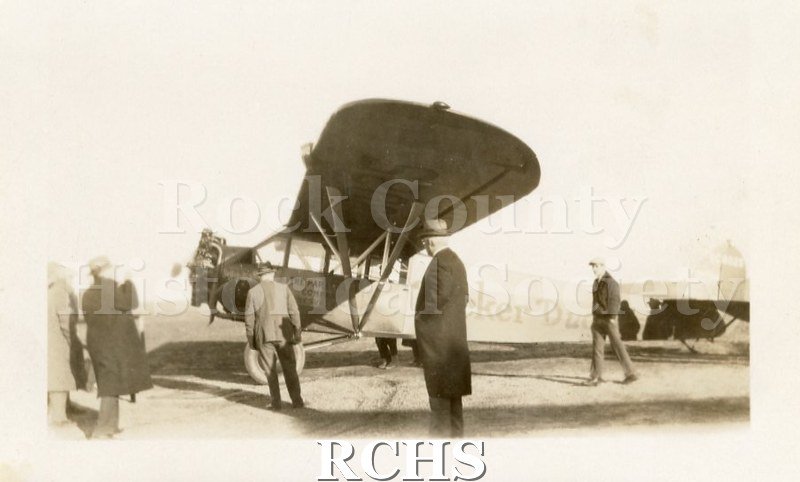 Black and white photograph of group of men standing next to the Parker Pen Co. Fairchild "Duofold" Plane. Possibly pictured is George Parker.