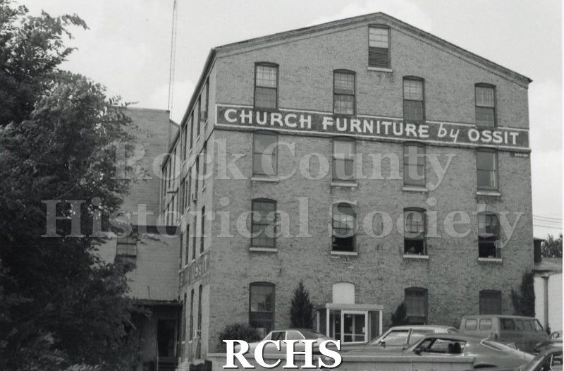 Black and white photograph of Ossit Church Furniture building. Sign of front: "Church Furniture by Ossit".