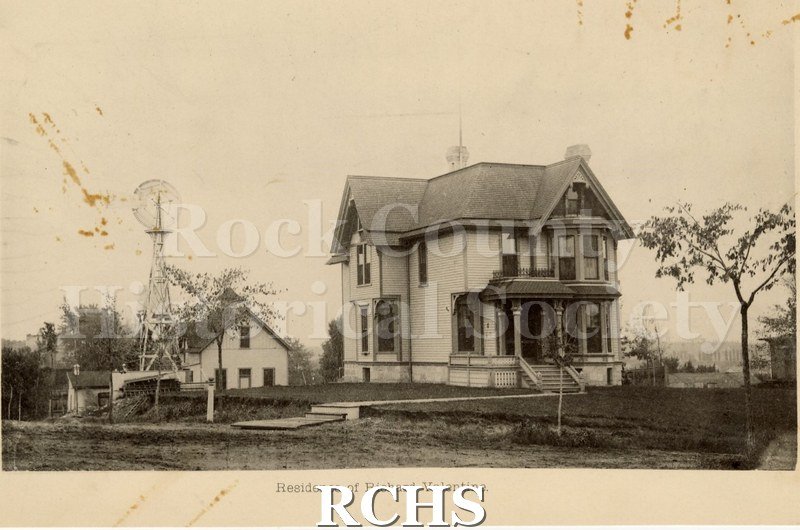 Black and white photograph of the residence of William D. Sutherland. Shows a two story house with a porch. There is a windmill on the left side.
