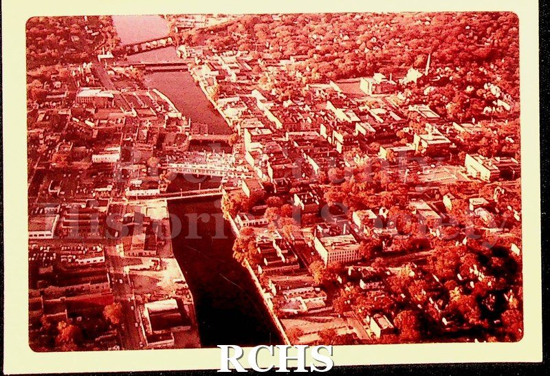 Color photo of Janesville, 1979. Looking North up the Rock River. Dam, bridge, East Milwaukee Street, West Court Street, and West Centerway visible.