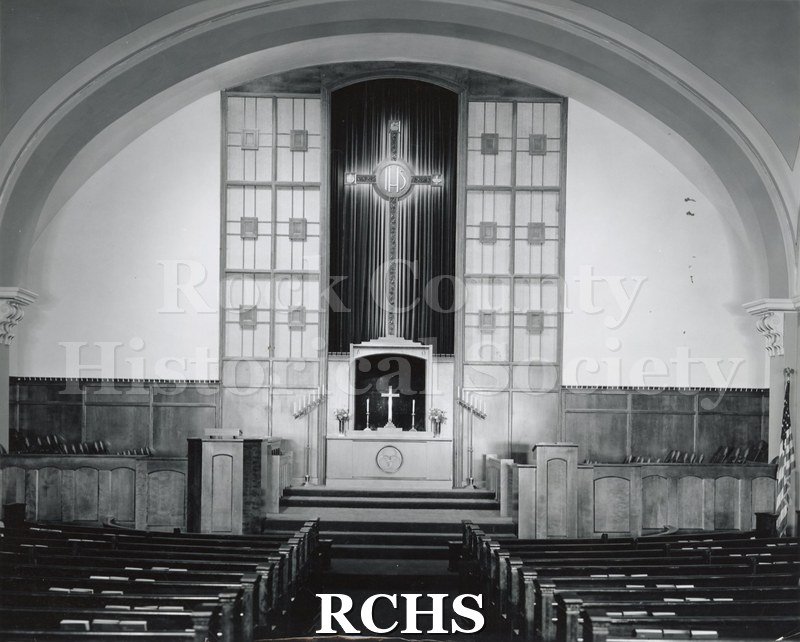 Black and white photograph of the interior of First Methodist Church, Newton, IA, with pews leading up to the altar area.