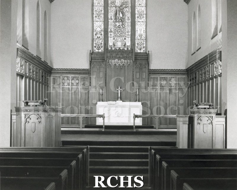 Black and white photograph of the interior of St. Paul's Lutheran Church, Janesville, WI, with a large stained glass window above the altar.