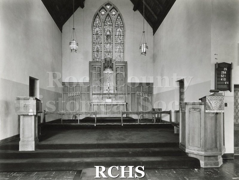 Black and white photograph of the interior of an unidentified church with a wooden altar .