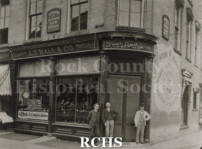 Black and white photograph of A.F. Hall & Co. building. The word Watches is above the window. On the side is a shield with "Webb & Hall Jewelry & Silverware".