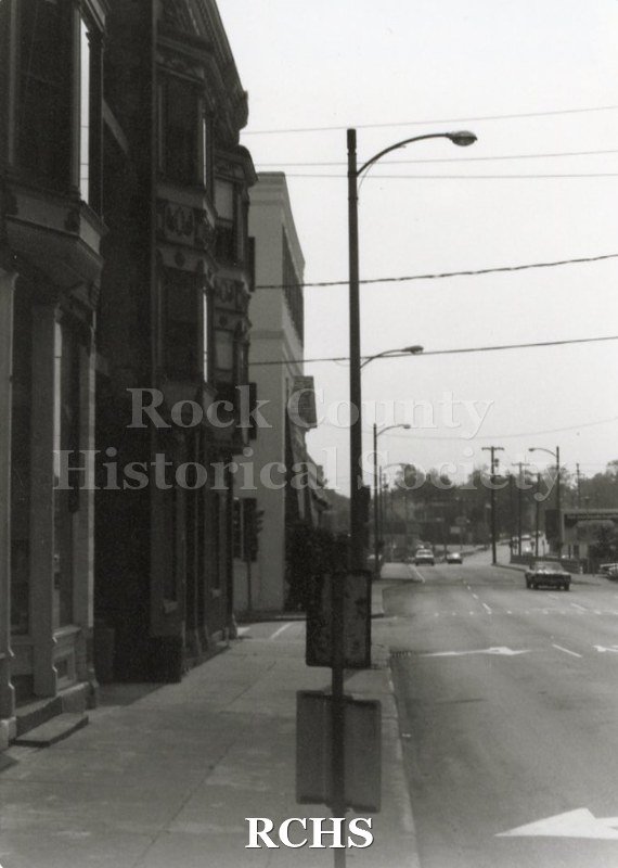 Black and white photograph of the Kent Block. This is a view of East Court Street with buildings on the left side and cars on the street.