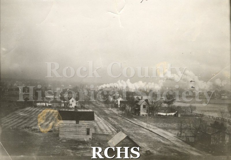 Black and white photograph of Armour Street in early Janesville with a dirt street in the middle and houses on each side.
