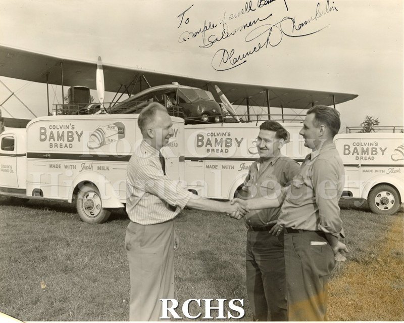 Black and white photograph of Mr. Bruni, Mr.Hanewall and Clarence Chamberlin standing in front of several delivery trucks with the name: "Colvin's Bamby Bread" on.