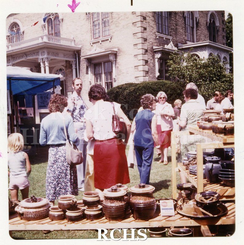 Color photo of the Tallman Arts Festival. There are several people standing on the grounds. An arrow points to Charles R. Tallman.