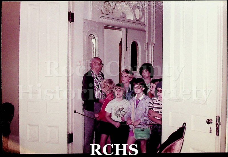 Colored photograph of unidentified school children looking at an exhibit in the Tallman House.