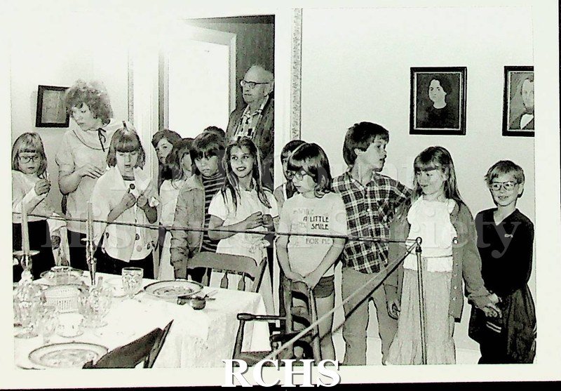 Black and white photograph of Washington School tour group looking at the exhibit in the dining room of the Tallman House.