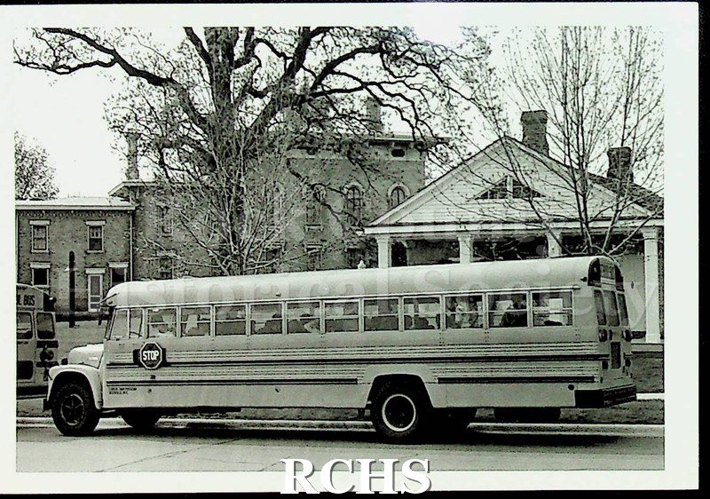 Black and white photograph of an unidentified school bus in front of the Stone House.