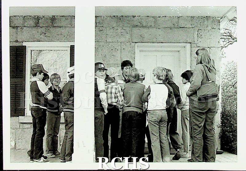 Black and white photograph of an unidentified group of students and teacher standing on the porch of the Stone House.