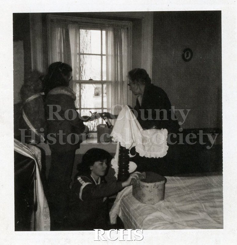 Black and white photograph of Ruth N. Hughes, Mary Nelson, and Emily DeBroux. One has a tablecloth in her hand and another is kneeling by the bed.