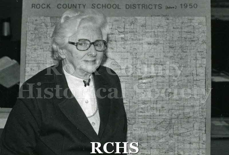 Black and white photograph of Mildred Rye standing in front of a map.