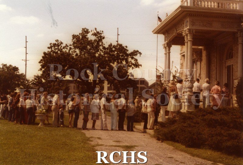 Colored photograph of 1979 Art Festival. Shows people lined up at the entrance to the Tallman House.