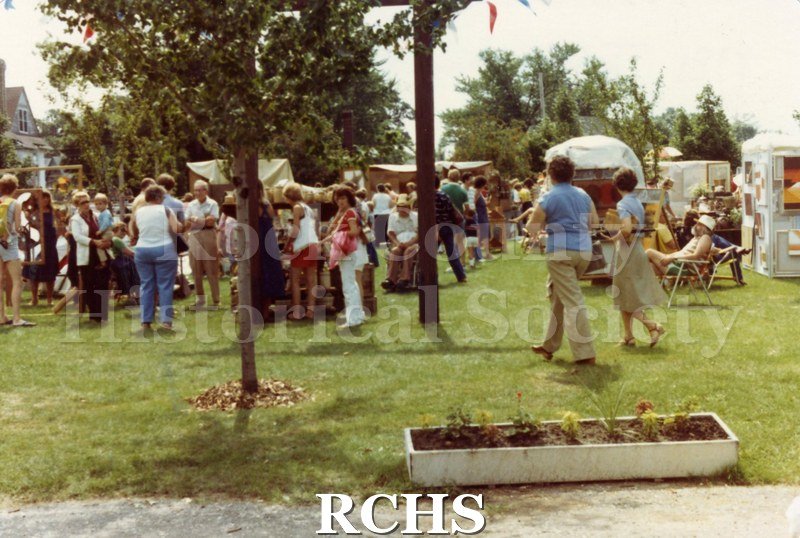 Colored photograph of people strolling the grounds at the 1981 Tallman Arts Festival. All have their backs to the camera.