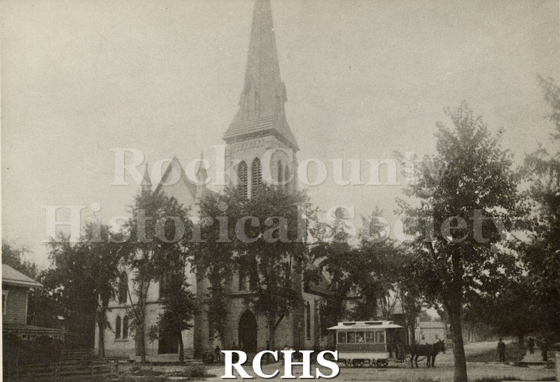 Black and white photograph of First Congregational Church with people standing in front of it. There is a wagon pulled by a mule on the right side.