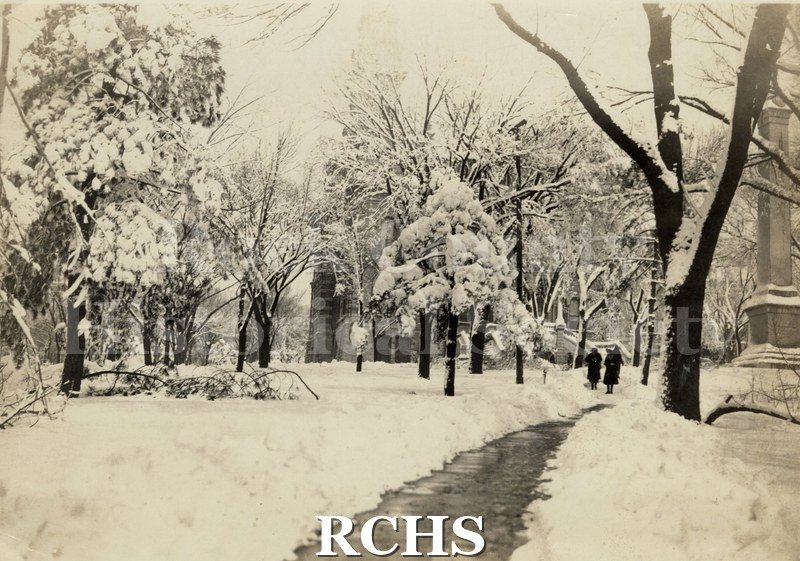 Black and white photograph of Court House Park 1911. Two people are walking toward the Rock County Court House in the winter.