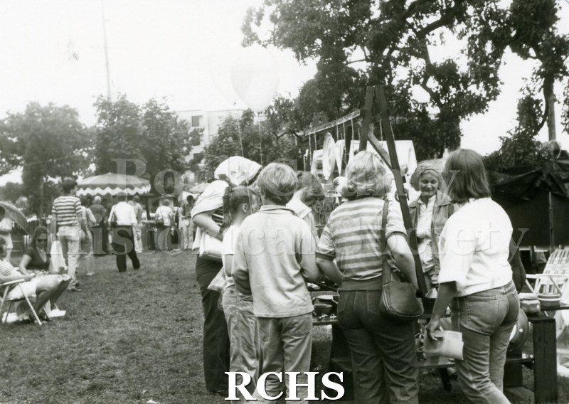 Black and white photograph of several people standing around various exhibits.